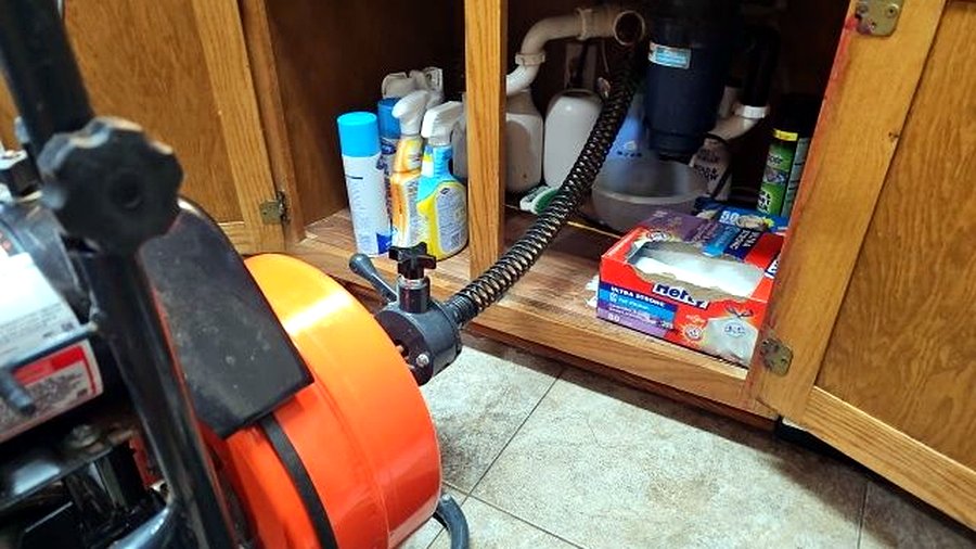 Drain snake machine clearing a kitchen sink drain